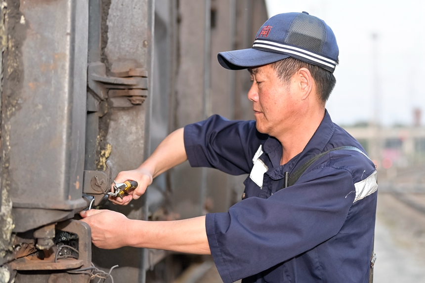 哈南站貨檢車間下行五場(chǎng)貨運(yùn)檢查員正在對(duì)車輛中門進(jìn)行捆綁加固。