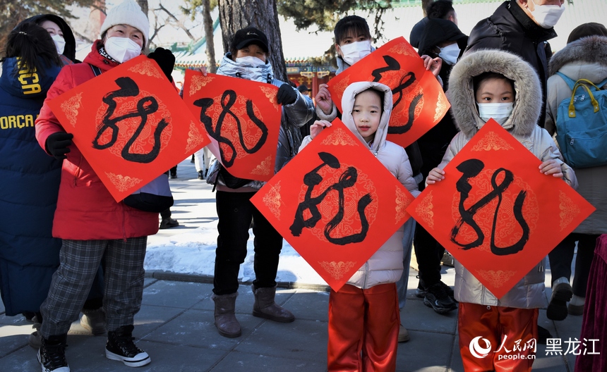 書法家揮毫潑墨書寫“龍”字，市民領(lǐng)取后進行展示。人民網(wǎng) 蘇靖剛攝